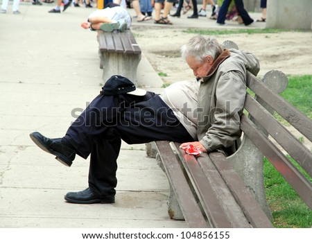 TORONTO - MAY 27: A man sleeps on a bench on May 27, 2012 in Toronto. Costs of homelessness in Canada in 2007 was between $4.5 to $6 billion in emergency services and community organizations.
