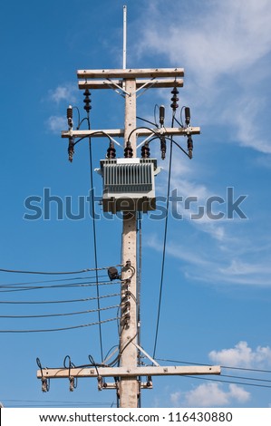 Energy and technology: electrical post by the road with power line cables, transformers  against bright blue sky providing copy space.