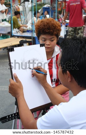 CHIANG MAI,THAILAND-JUNE 23 : an artist who draw portraits for customer, 30 minute wait for a picture ,On June 23, 2013 in Chiang Mai, Thailand.