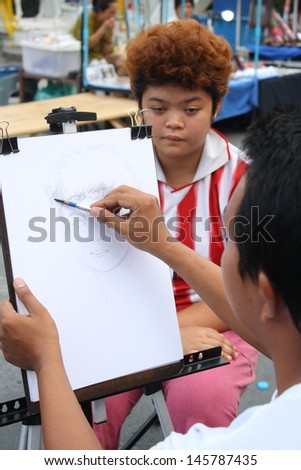 CHIANG MAI,THAILAND-JUNE 23 : an artist who draw portraits for customer, 30 minute wait for a picture ,On June 23, 2013 in Chiang Mai, Thailand.
