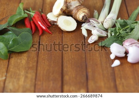 food ingredients of lemon grass soup (spicy Thai soup  or Tom Yam) include galangal, lime leaves, lime, lemon grass and red chili on wooden background.