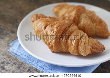 croissants in white dish  on blue cotton cloth place on wooden background