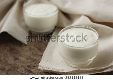 yogurt in glass on cotton cloth place on old wooden background. plain yoghurt.