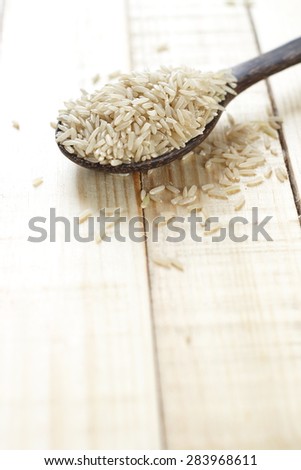 uncooked brown rice in wooden spoon place on wooden background. organic product, organic brown rice.