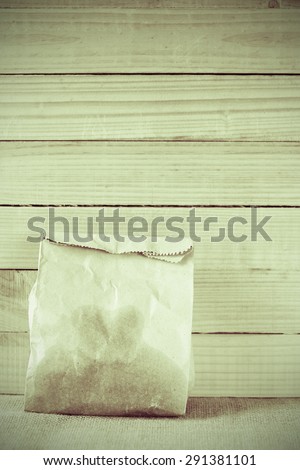 vintage colour style of paper bag of some food in front of wooden background.