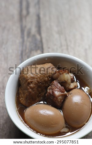 eggs boiled with tofu and pork belly in sweet gravy soup on wooden background.