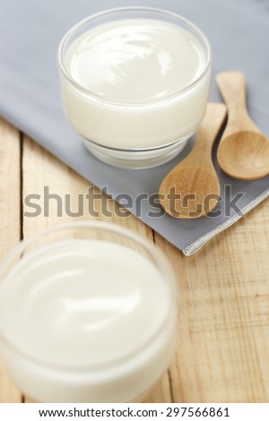 yogurt in glass cup on wooden background with grey cotton and wooden spoon. plain yoghurt. yogurt. yoghurt.