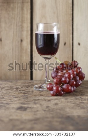 glass of red wine (wine cooler) and fresh grape on wooden background.