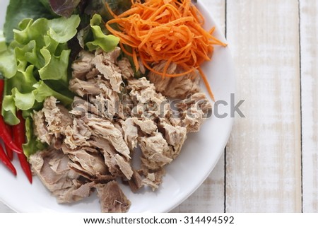 canned tuna fish with fresh vegetable on white dish. tuna. Canned tuna chunks. tuna place on white wooden table.