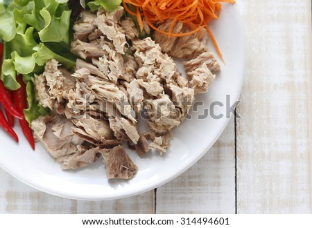 canned tuna fish with fresh vegetable on white dish. tuna. Canned tuna chunks. tuna place on white wooden table.