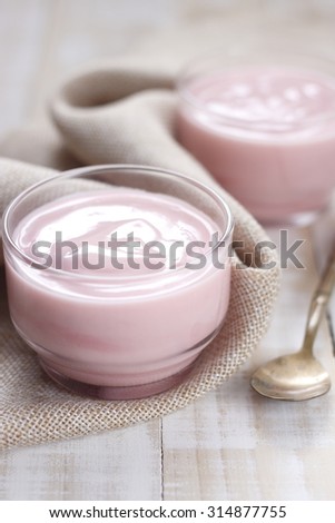 strawberry yogurt on wooden white background. strawberry yoghurt with vintage spoon. pink yogurt.