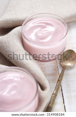 strawberry yogurt on wooden white background. strawberry yoghurt with vintage spoon. pink yogurt.