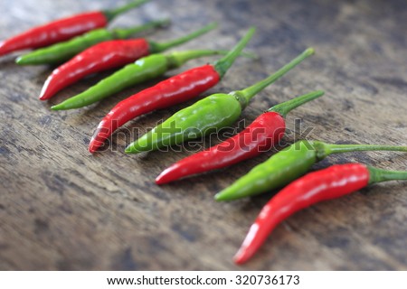 fresh red and green chilli on old wood background. guinea pepper ; bird pepper ; bird-chilli ; small capsicum ; chilli pepper ; tiny fiery chilli ; hot chilli .