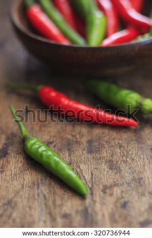 fresh red and green chilli in wooden cup on old wood background. guinea pepper ; bird pepper ; bird-chilli ; small capsicum ; chilli pepper ; tiny fiery chilli ; hot chilli .