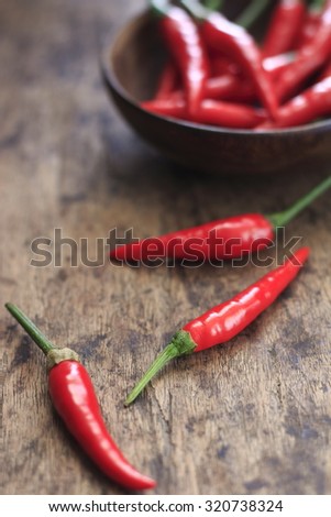 fresh red chilli in wooden cup on old wood background. guinea pepper ; bird pepper ; bird-chilli ; small capsicum ; chilli pepper ; tiny fiery chilli ; hot chilli .