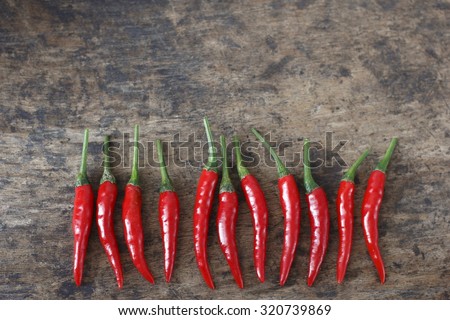 fresh red  chilli on old wood background. guinea pepper ; bird pepper ; bird-chilli ; small capsicum ; chilli pepper ; tiny fiery chilli ; hot chilli .