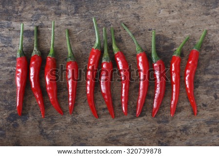 fresh red  chilli on old wood background. guinea pepper ; bird pepper ; bird-chilli ; small capsicum ; chilli pepper ; tiny fiery chilli ; hot chilli .