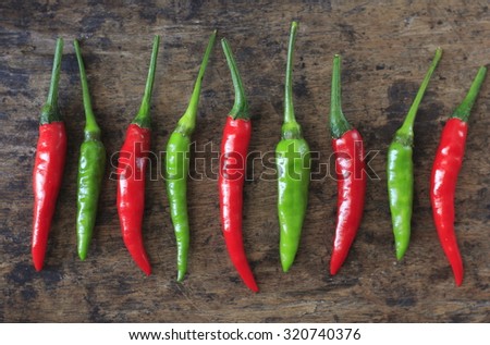 fresh red and green chilli on old wood background. guinea pepper ; bird pepper ; bird-chilli ; small capsicum ; chilli pepper ; tiny fiery chilli ; hot chilli .