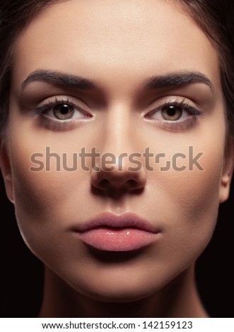 Beauty closeup of fresh young female. Beautiful bright eyes, tied brown hair, daily natural make-up and lips covered with caviar. Dark background.