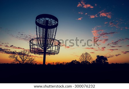 Silhouette of disc golf basket against sunset. Vintage filter effects.