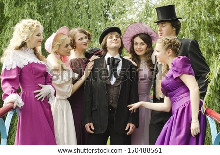 Women dressed like old fashionable ladies are looking at a young gentleman