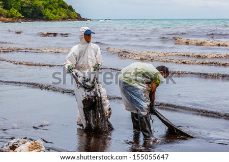 RAYONG,THAILAND-July 31: Workers are helping to clean and move the crude oil from the beach on oil spill accident on Ao Prao Beach at Samet island on July 31,2013 in Rayong,Thailand