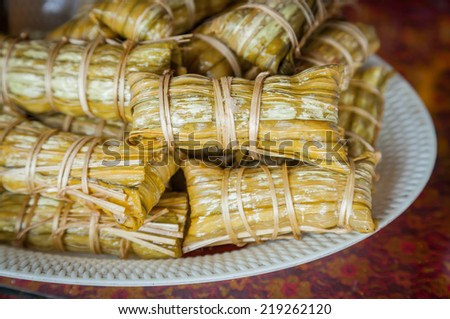 Thai traditional sticky rice dessert in banana leaf packaging.Bananas with Sticky Rice.