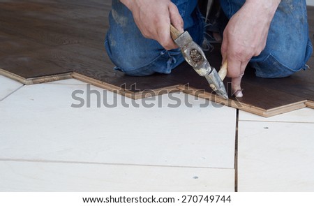 Worker puts oak parquet and hammered nails into it.