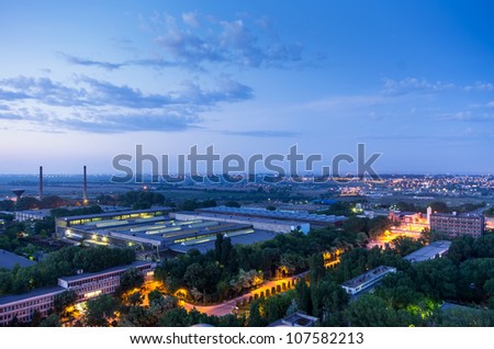 industry buildings near small city with lights after sunset