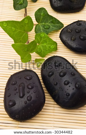 closeup of spa balck stones with water-drops on bamboo board