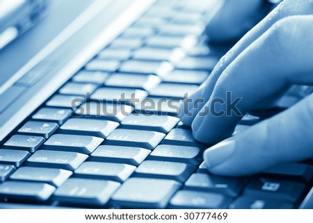 man hands typing on laptop keyboard blue toned
