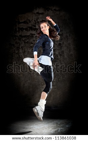 Dancing woman with brown long hair and happy facial expression jumping up.