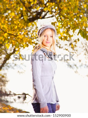 Young woman relaxing under a tree by the river. Autumn set.
