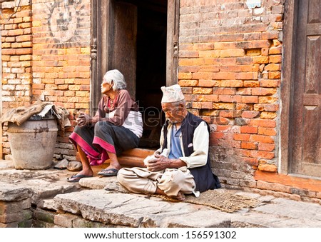 BHAKTAPUR,NEPAL-MAY 20:Old woman and man sitting intertwined their homes on May 20, 2013, Bhaktapur,Nepal.Bhaktapur is one of 3 Royal cities in the Kathmandu Valley and considered a cultural gem.
