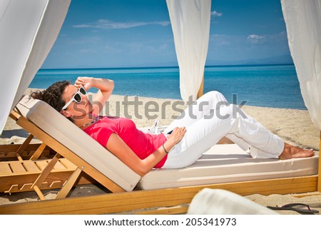 Woman relaxing on luxury bed at the sea beach. Greece.