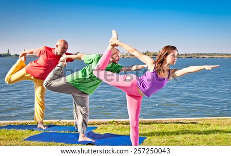 Tree people practice Yoga asana at lakeside on suny day. Yoga concept.