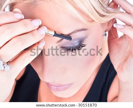 A beautiful young woman having the final touches applied to her make up on a eyebrow