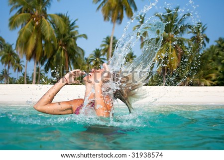 Beautiful woman throw back hair from the water at the tropical beach