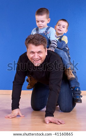 Attractive father giving sons a ride , happy family . Studio shot