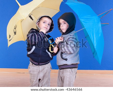 Twins brother  have fun under an umbrellas, studio shot