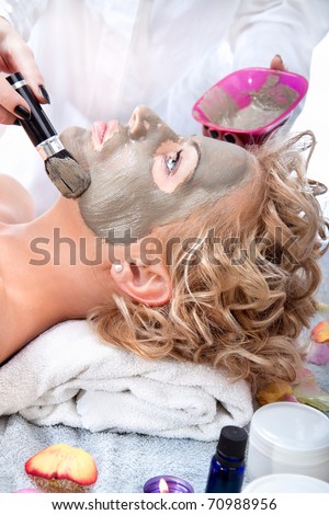 Applying mud face pack on woman face with brush