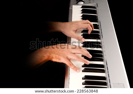 handsome young man playing the piano isolated in dark background