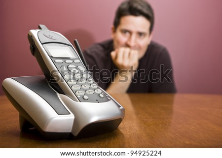 A man nervously waits for the phone to ring