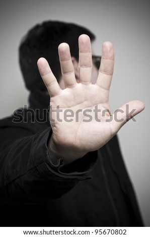 Mystery man holding up hand and looking away