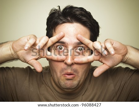 A man pulls a funny face while staring through his fingers