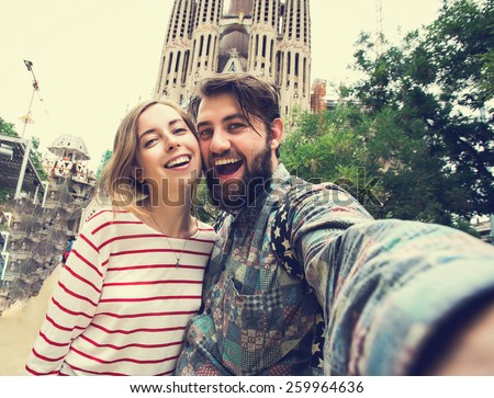 Happy young urban couple takes selfie self portrait photo with smart phone camera near Sagrada Familia while travel in Barcelona, Spain