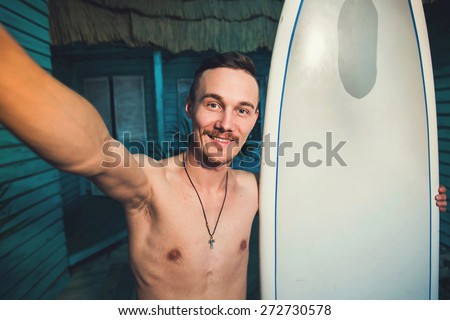 A young hipster surfer making selfie with his surf at beach house at ocean side