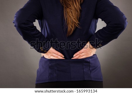 Closeup of businesswoman with back pain on gray background