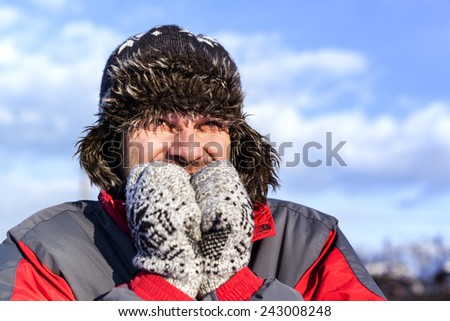 Young man with hat and coat shivering from cold in winter