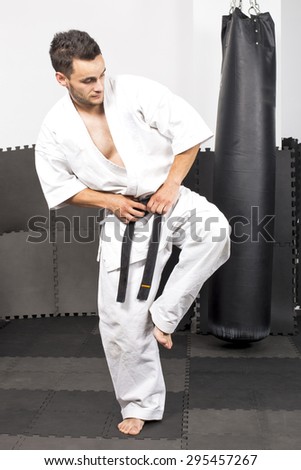 Full length portrait of young man in kimono training ashihara martial art at the gym